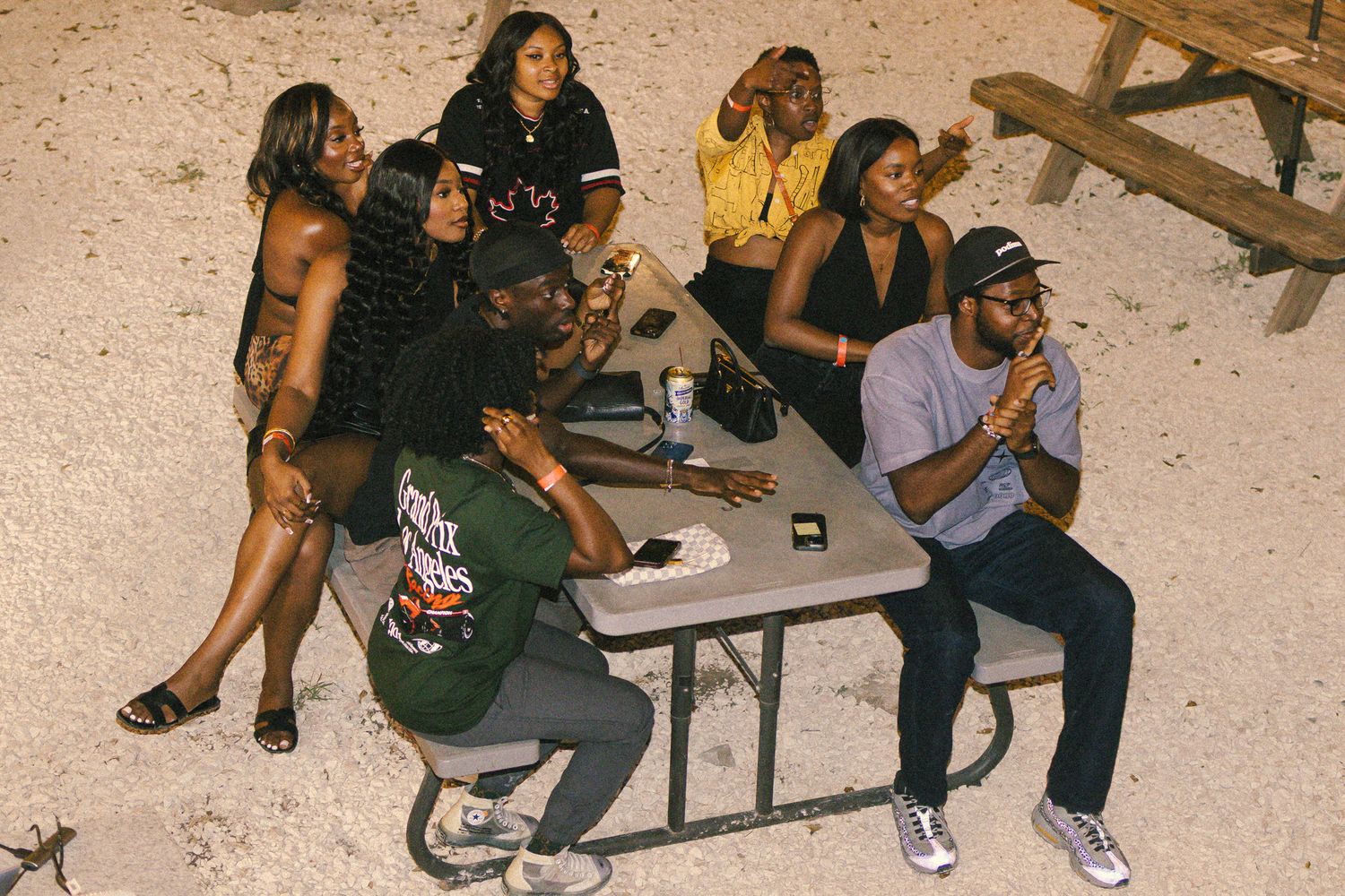 Students seated at tables during an evening outdoor event.