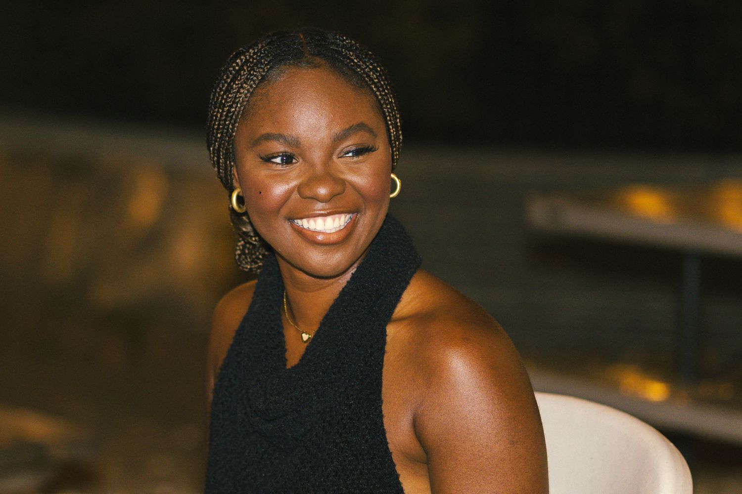 Person wearing a black sleeveless top with braided hair at an evening event.