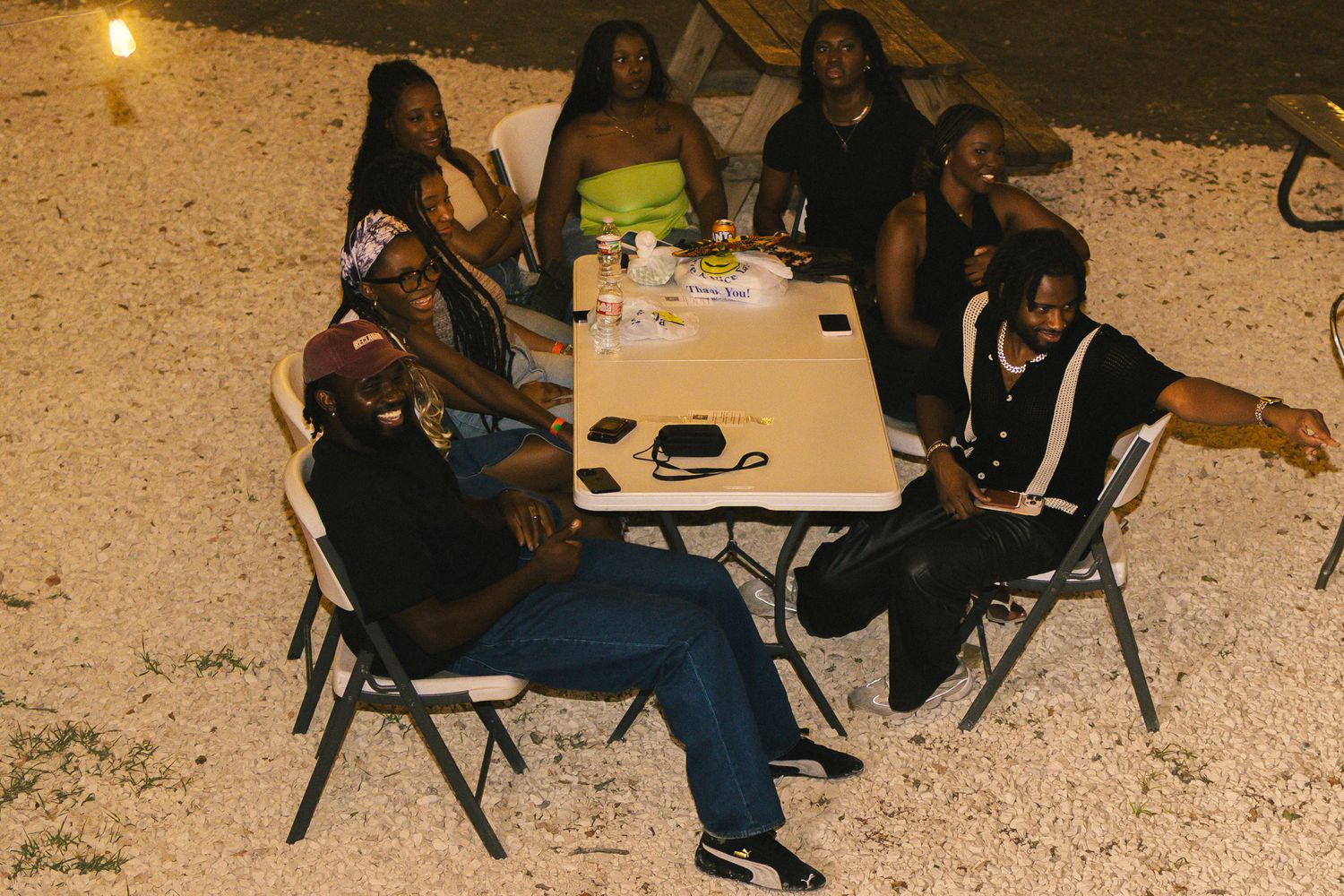 People gathered at outdoor tables having a social gathering at dusk.