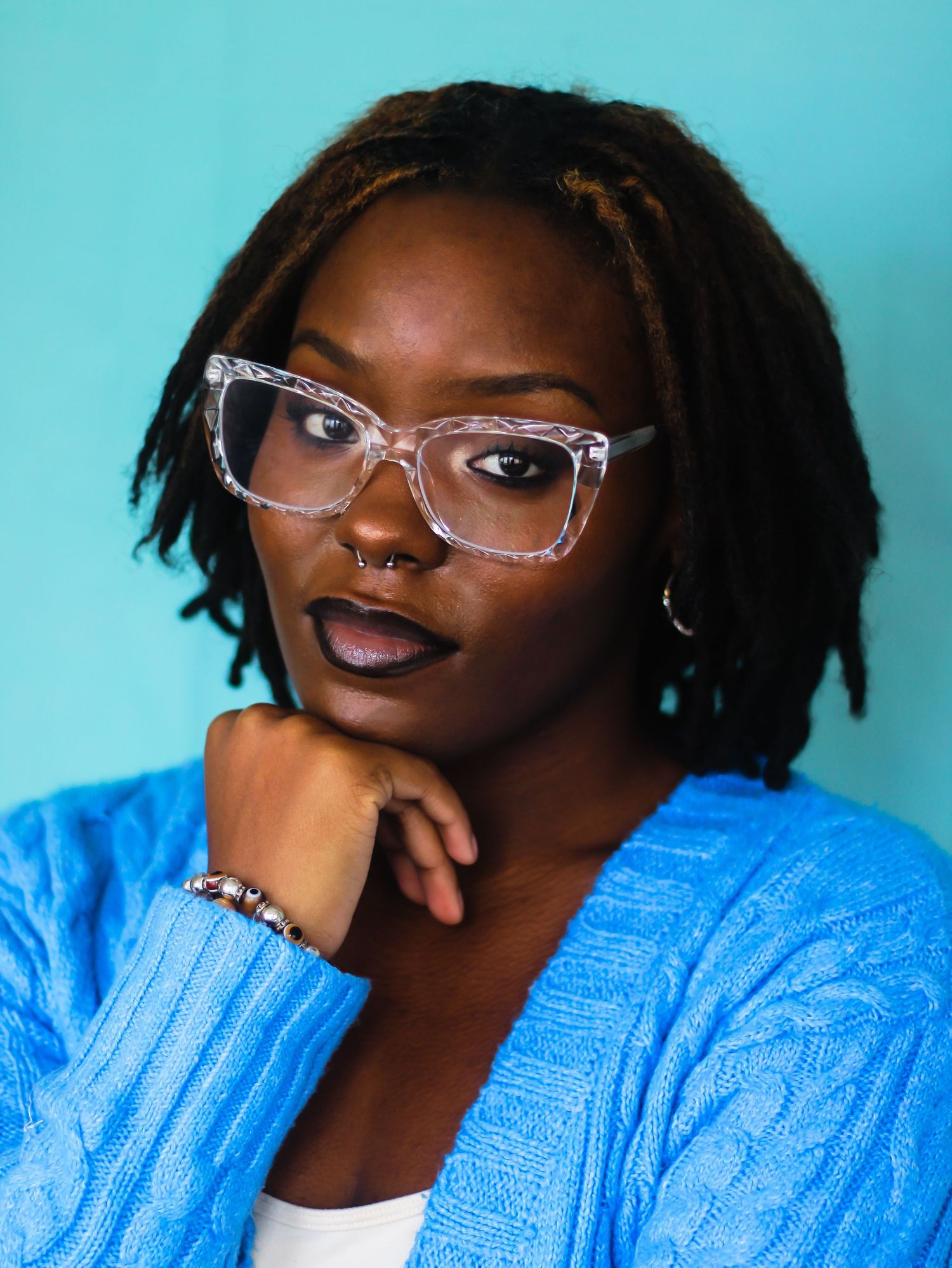 Studio portraits with turquoise background featuring casual poses and clear glasses.