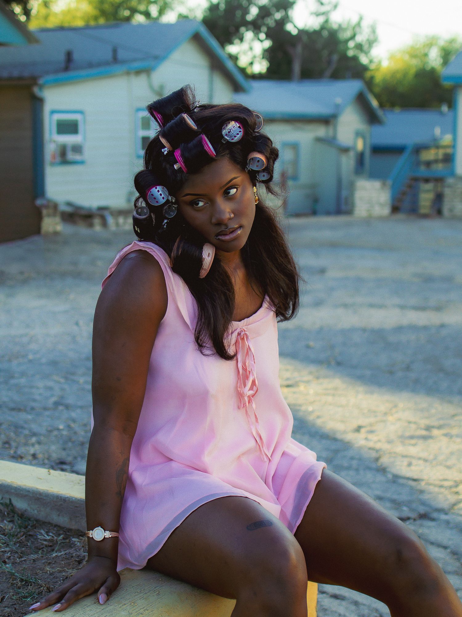 Candid summer photoshoot featuring pink clothing and retro hair accessories.