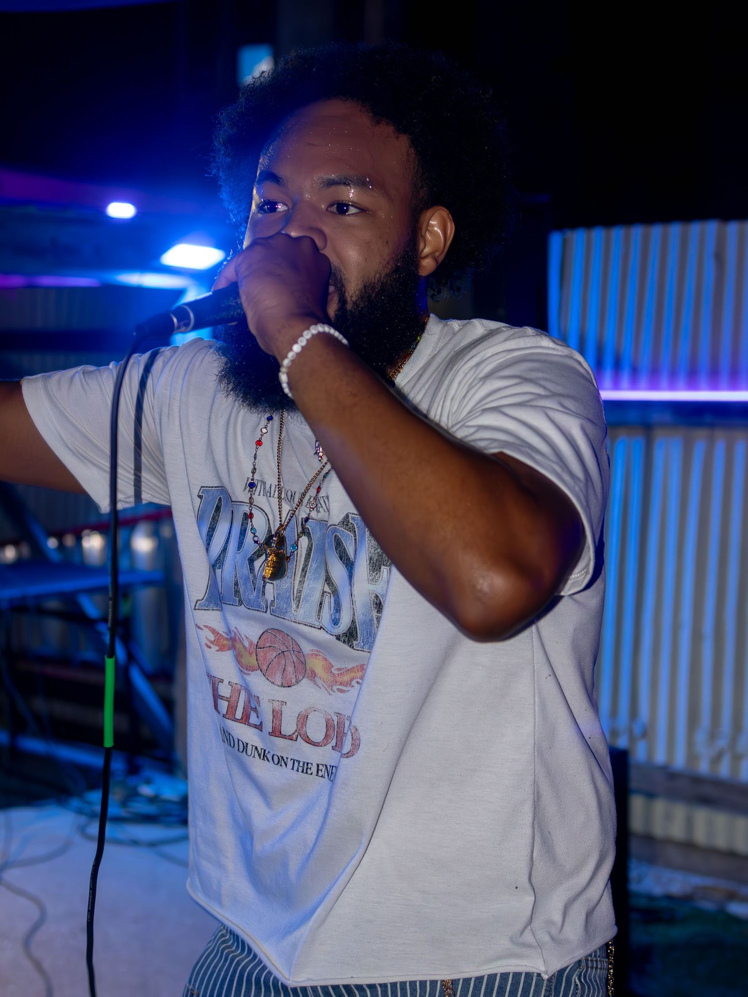 Singer performing passionately against dark background with blue stage lighting.