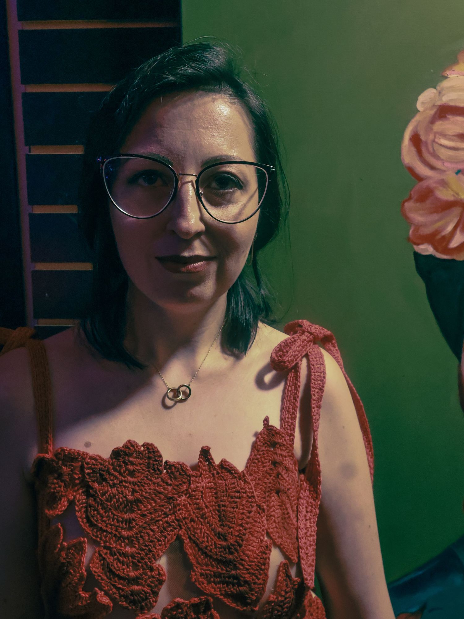 A red lace dress with intricate detailing is shown in a series of close-up photos against a dark background.