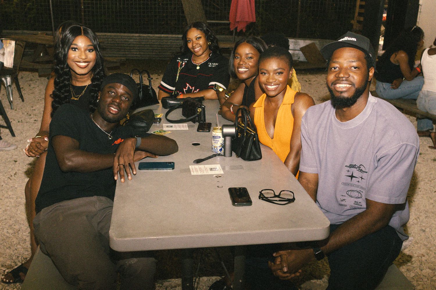 Friends socializing at outdoor tables during a casual nighttime event.