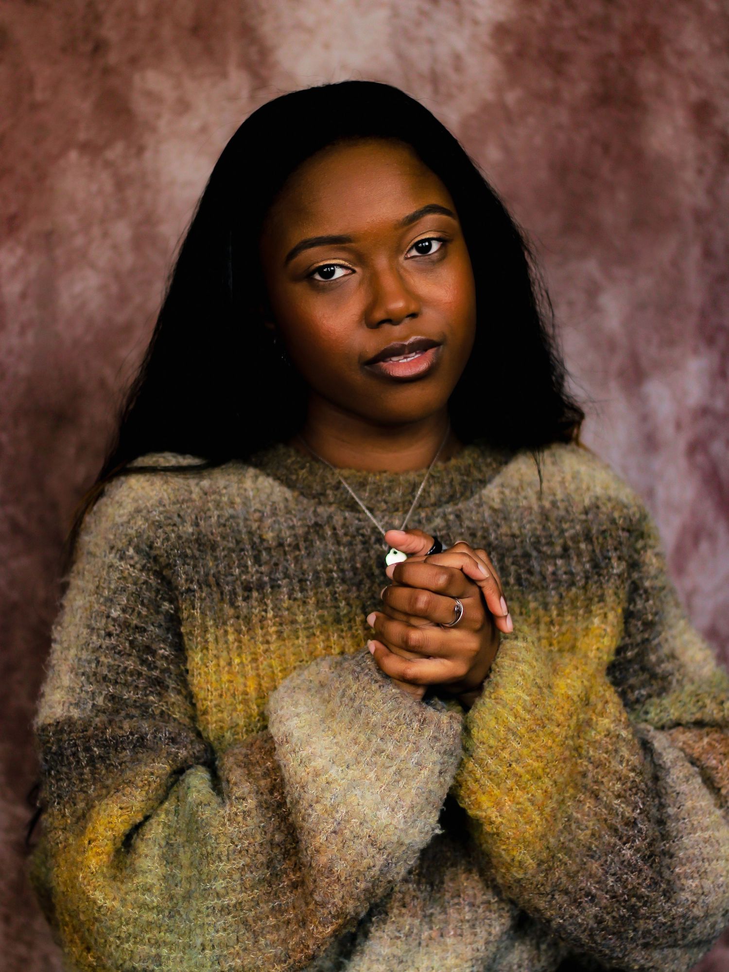 Portrait series showing expressions while wearing a cozy gray knit sweater against a textured brown backdrop.