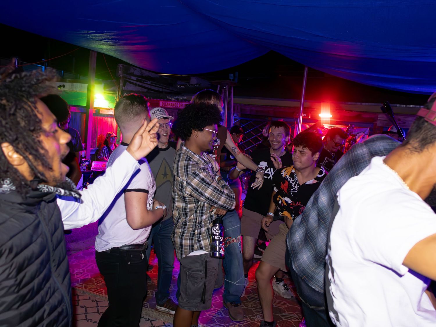 People dancing and moving at a nightclub with blue and red lighting effects.