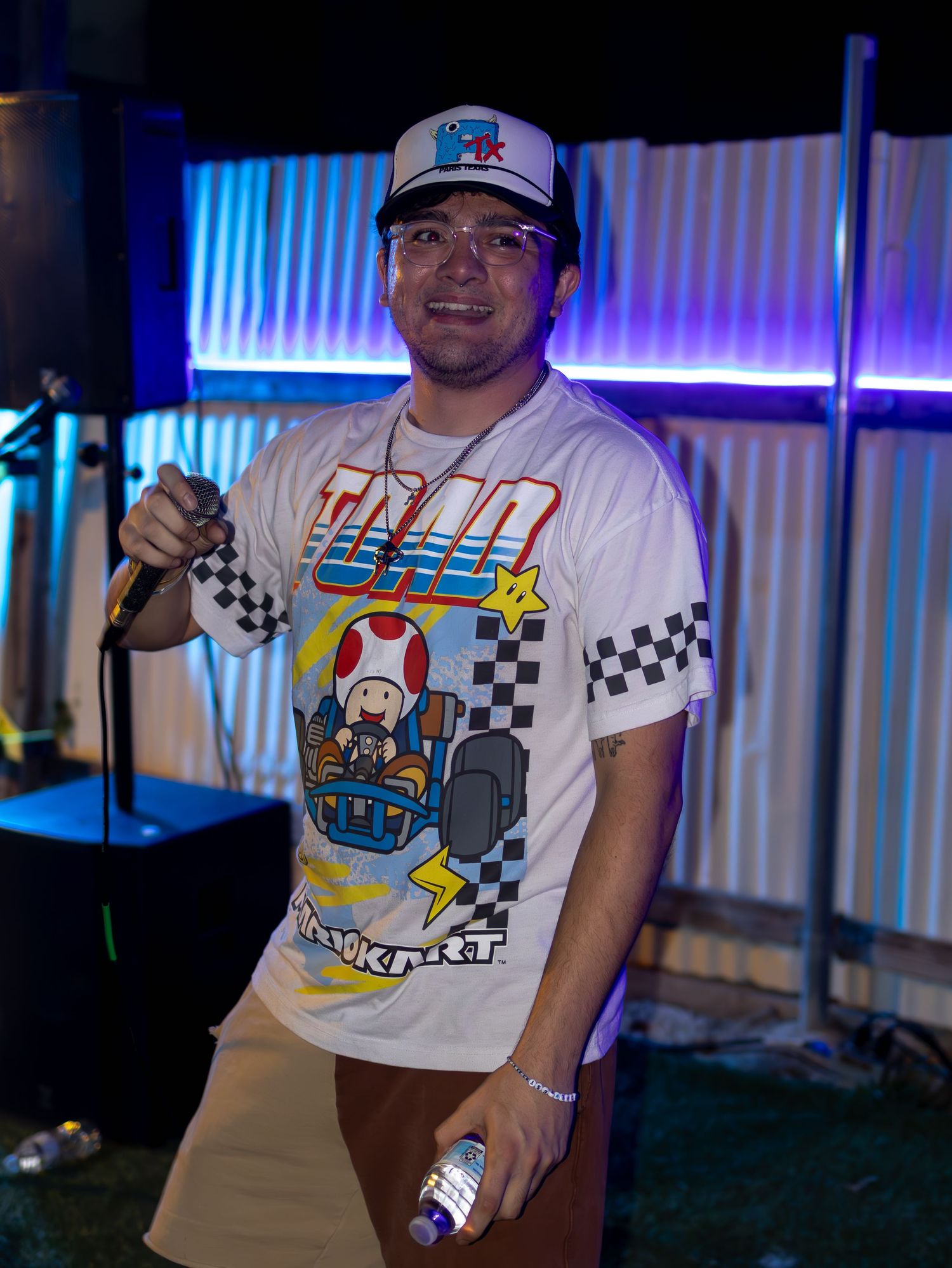 Stage performer in Nintendo-themed apparel entertaining crowd under blue and purple lighting.