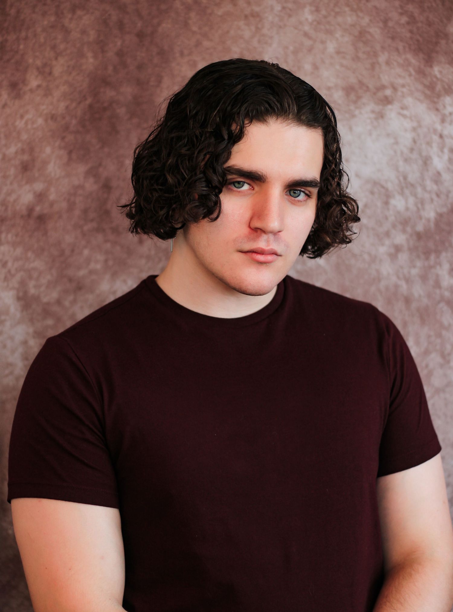 Studio portraits in dark t-shirt showing various poses against textured brown background.