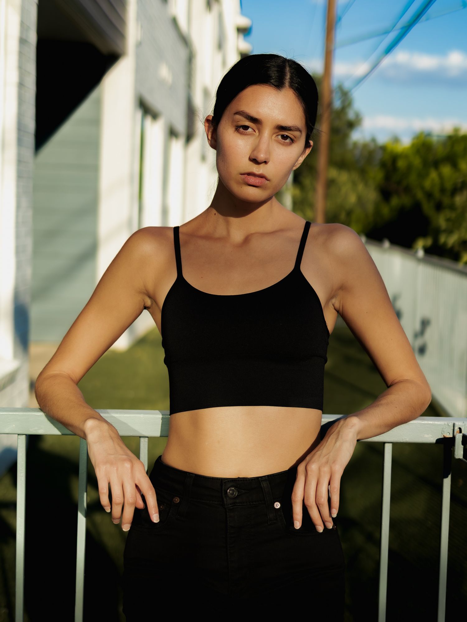 Portrait series in natural lighting showing artistic poses against white architecture outdoors.