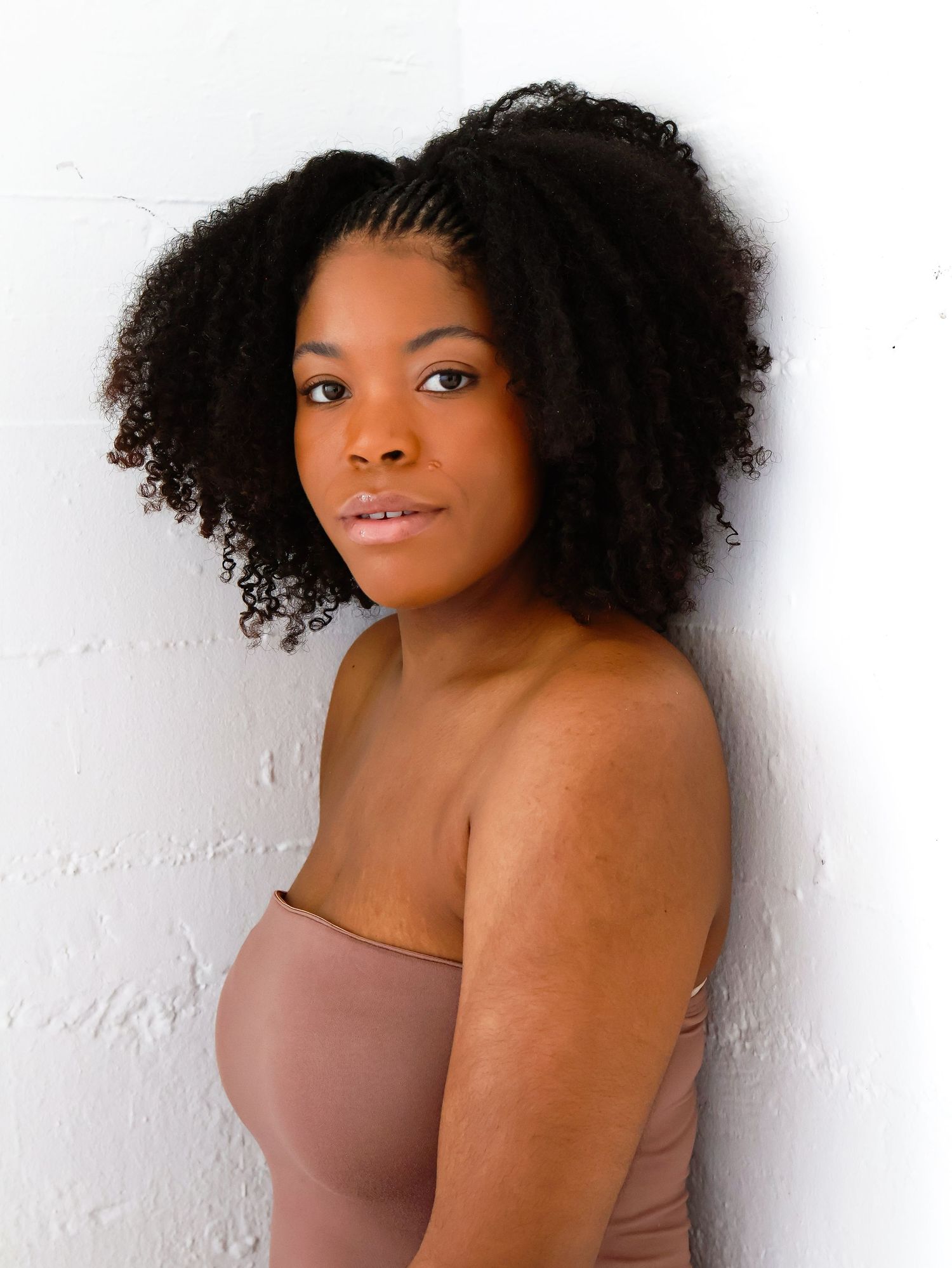 Studio portrait against white background showcasing natural curly hair.