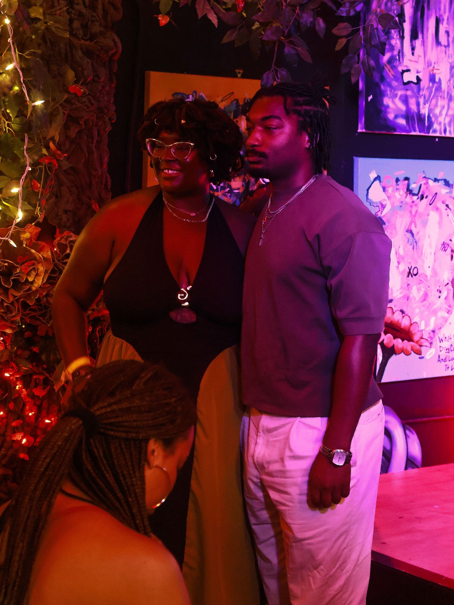 Two people enjoying a festive nightclub atmosphere with purple lighting and decorative elements.