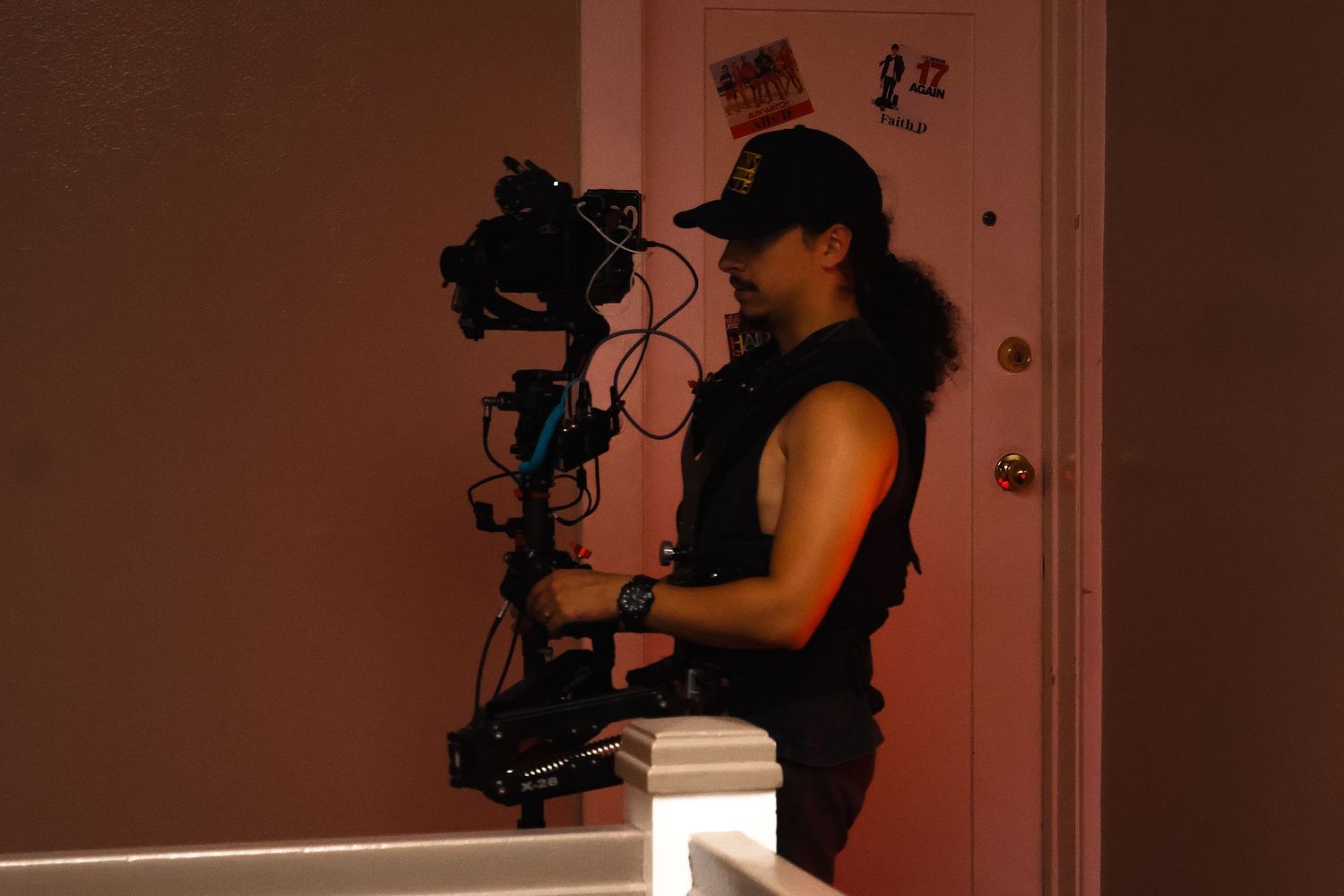 Behind the scenes film crew silhouettes working in dark hallway with dramatic red lighting.