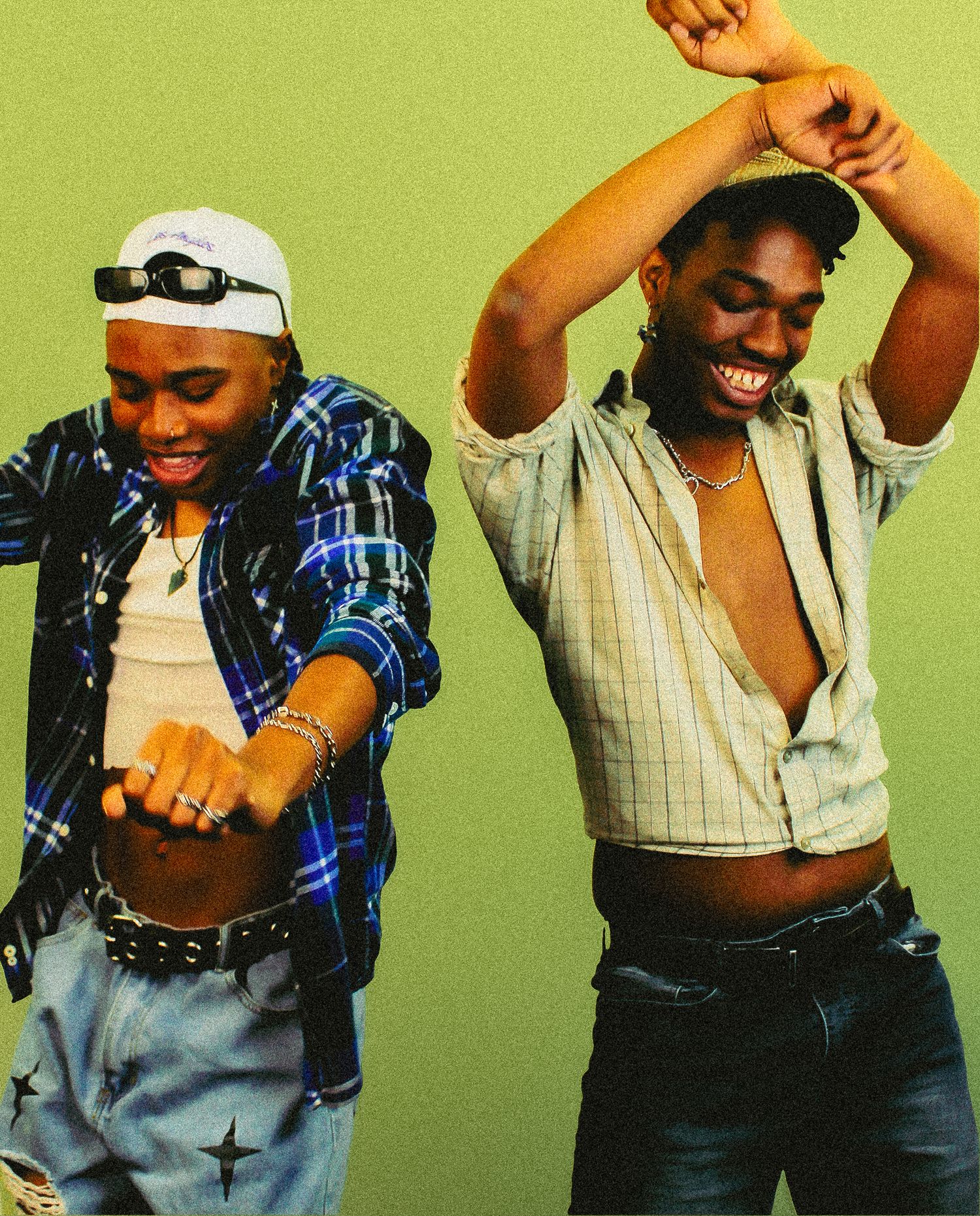 Two young men dancing energetically with shirts open against a green background.