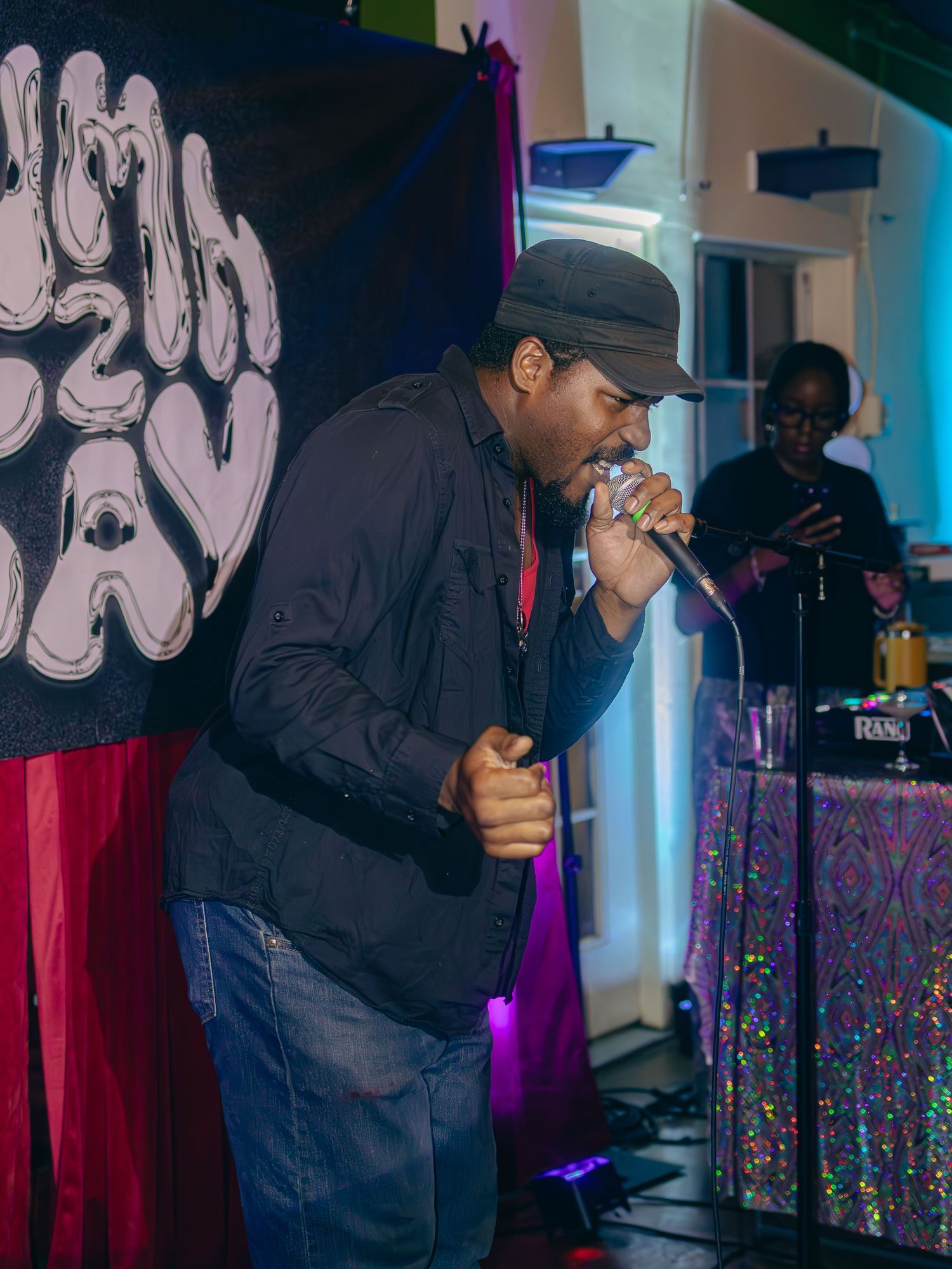 Singer performing with intensity against urban art backdrop and colorful stage lighting.