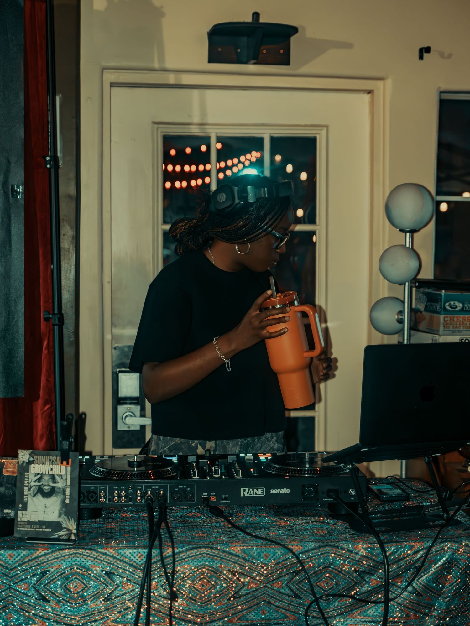 DJ equipment setup on table with turntables and mixer in dimly lit venue.