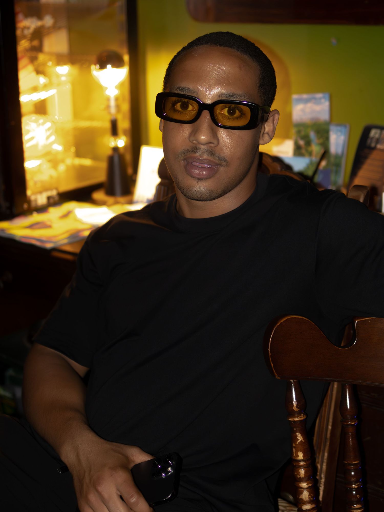 Person in black attire sits at a bar under warm lighting.