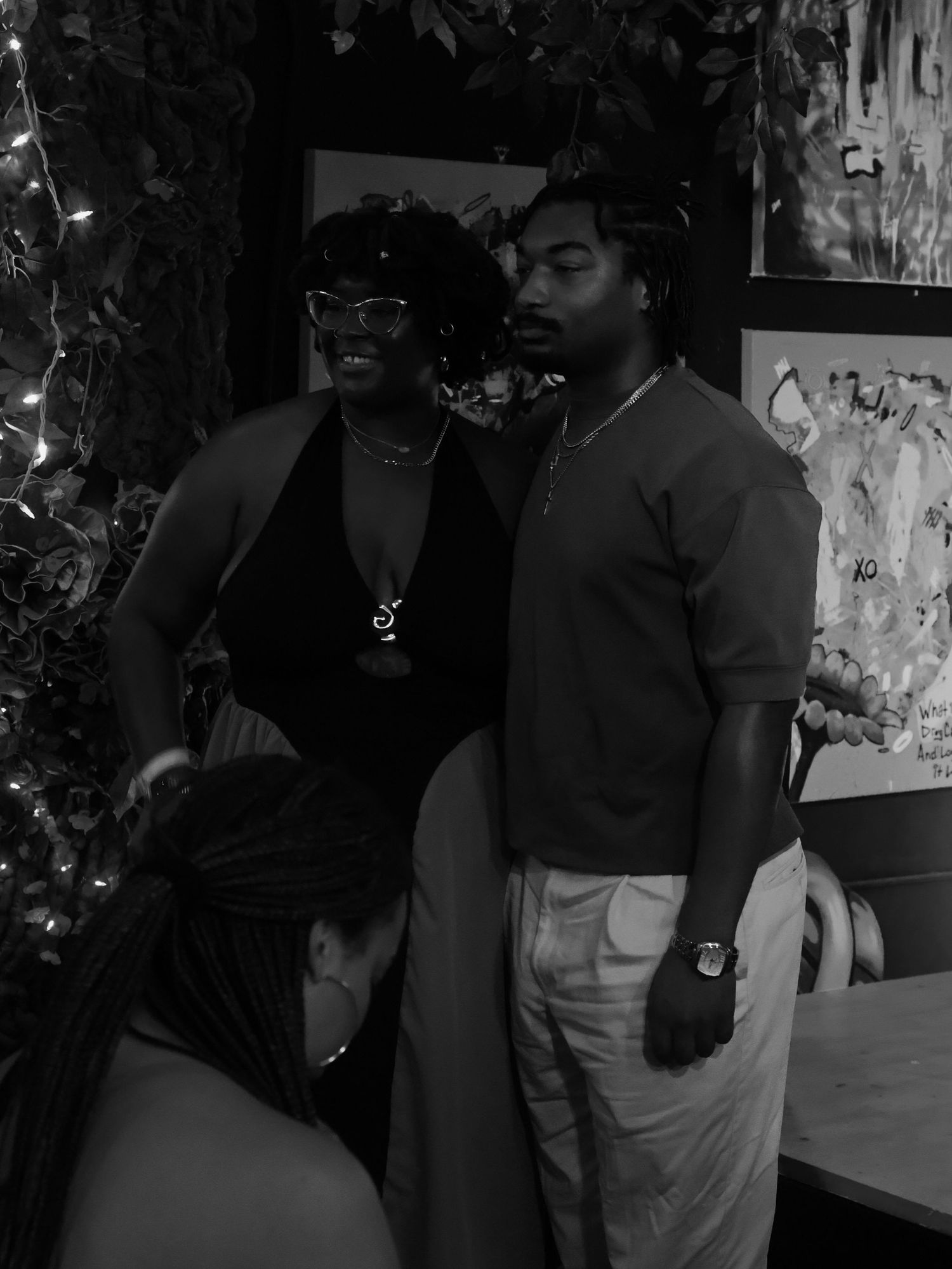Black and white photograph capturing candid moments at a social gathering.