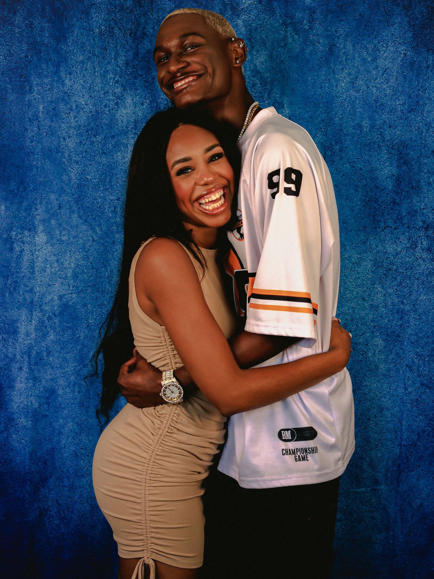 Happy couple embracing and laughing together in photo series with blue backdrop.