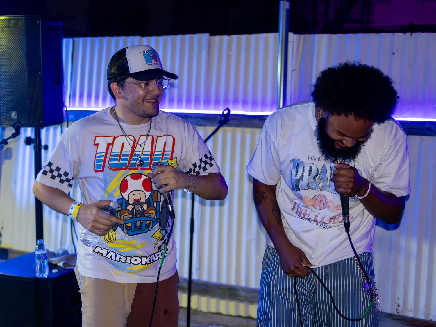Musicians in gaming-themed shirts performing under blue stage lights.