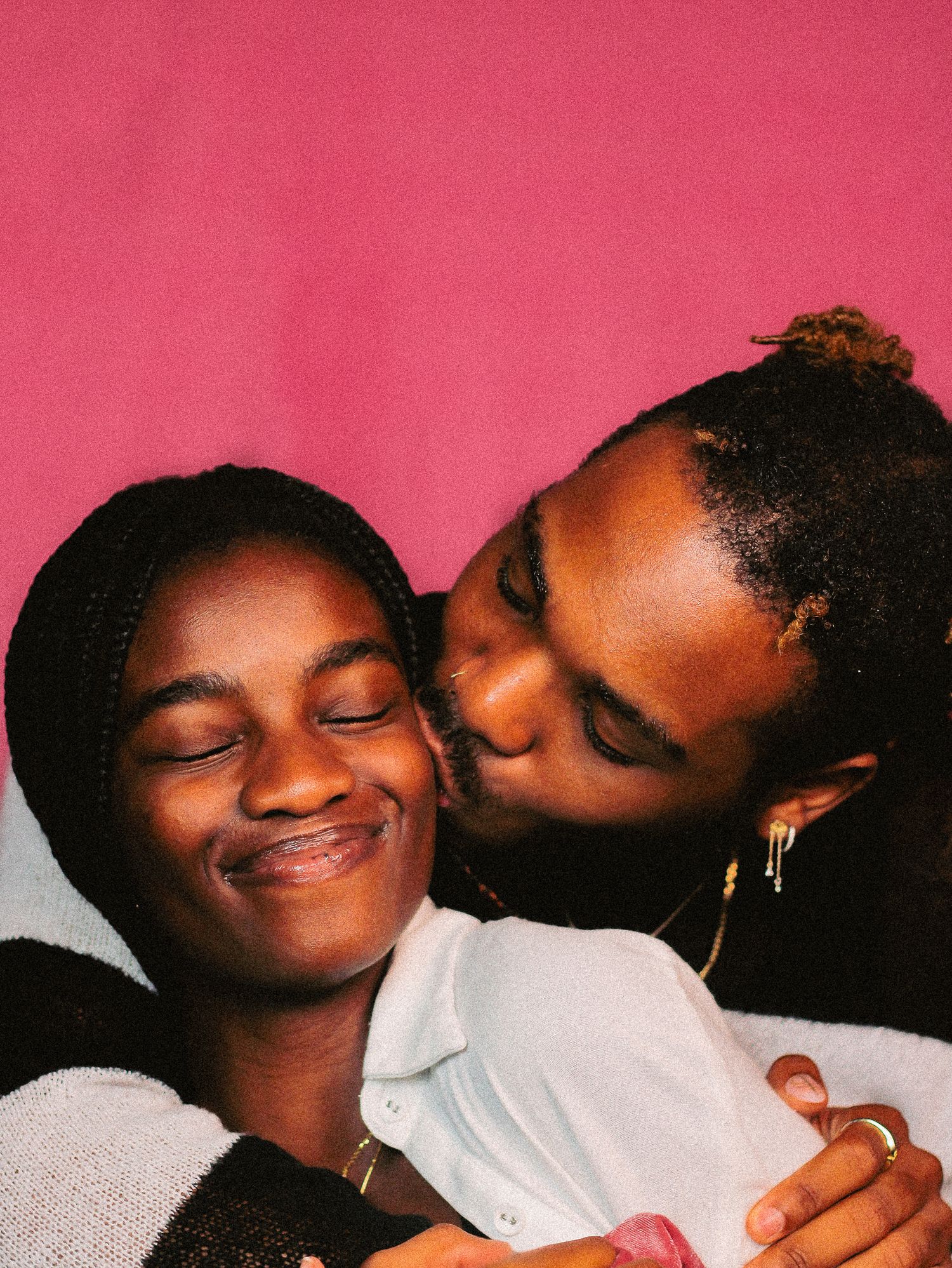 Playful moment captured against pink backdrop showing affection and joy.