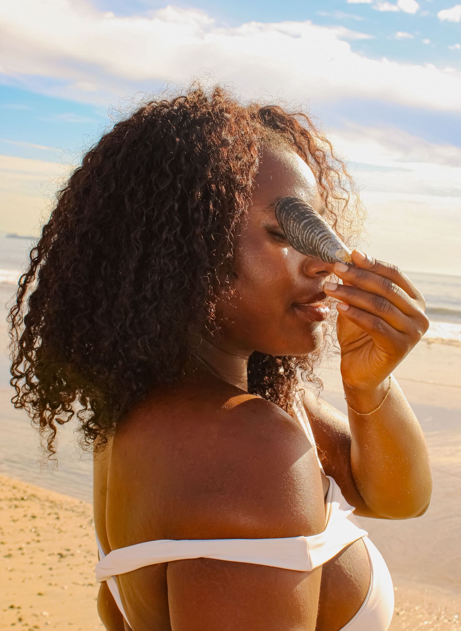 Artistic beach portrait with natural lighting and white swimwear.