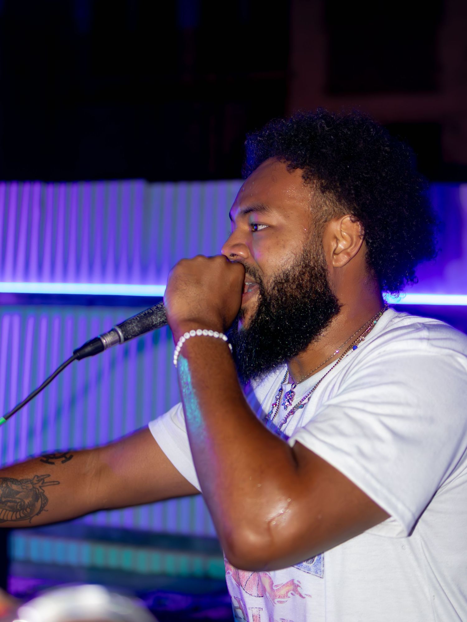 Singer grips microphone intensely during nighttime outdoor performance.