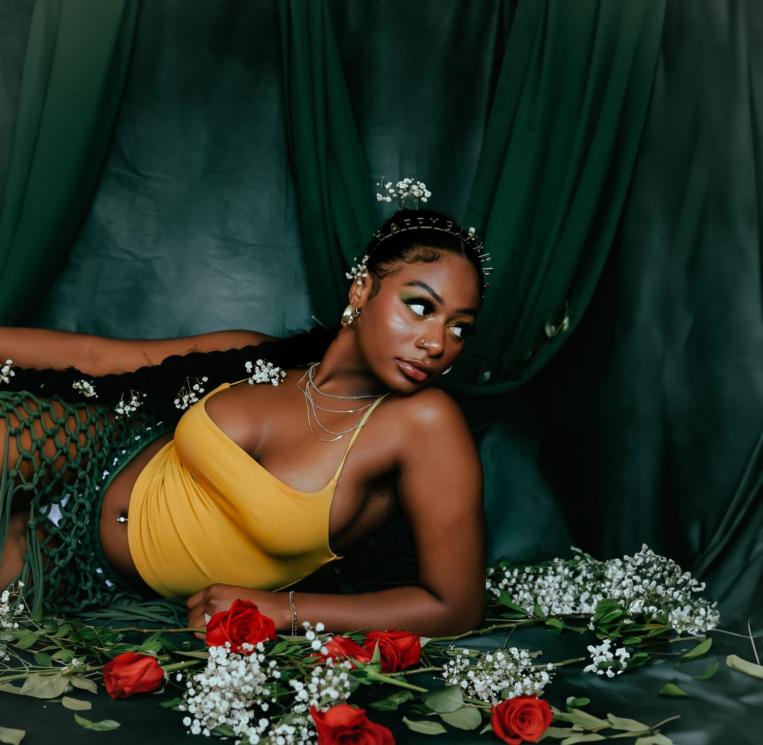 Dreamy portrait with scattered roses and baby's breath on dark green fabric.