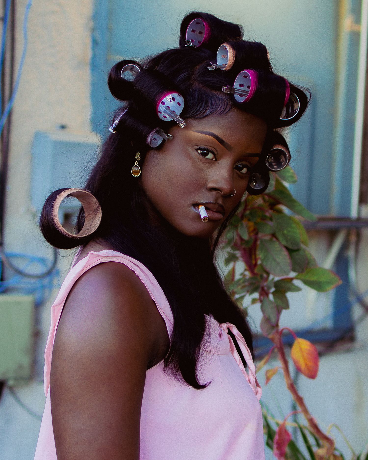 Fashion portrait with pink top and styled hair against soft blue background.