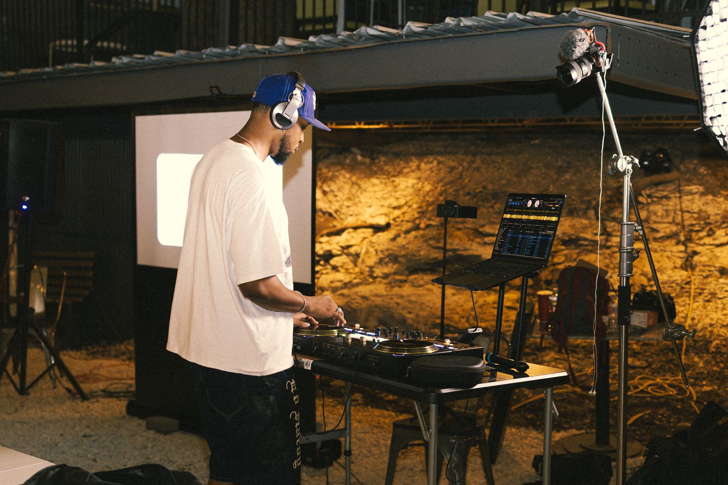 DJ equipment and speakers set up at an outdoor venue with stone walls.