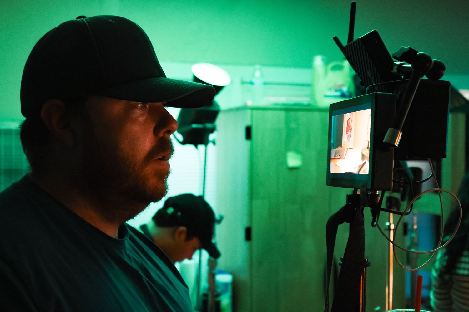 Film crew silhouetted against green lighting during a production shoot.