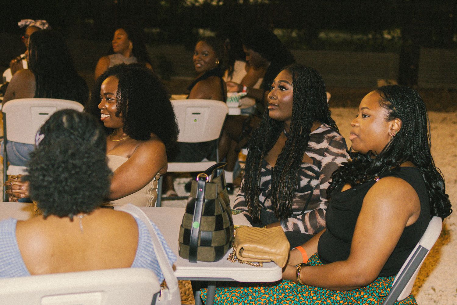 People enjoying conversation at outdoor tables during nighttime gathering.
