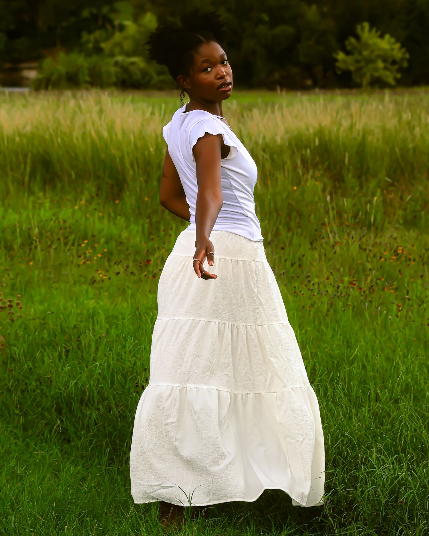 A flowing white dress twirls against a green grassy background in a summer field.