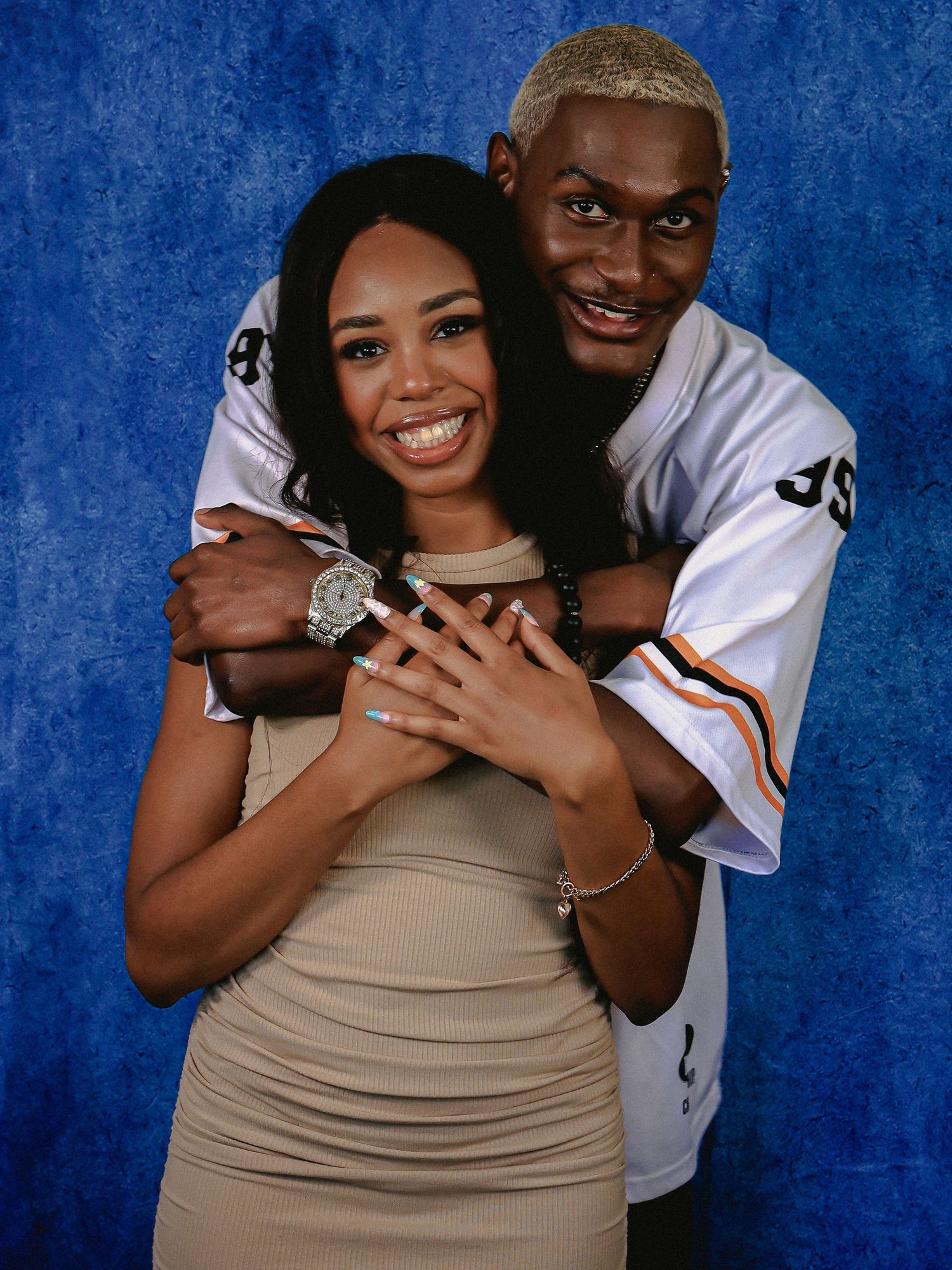 Couple embracing in studio portrait against blue background.