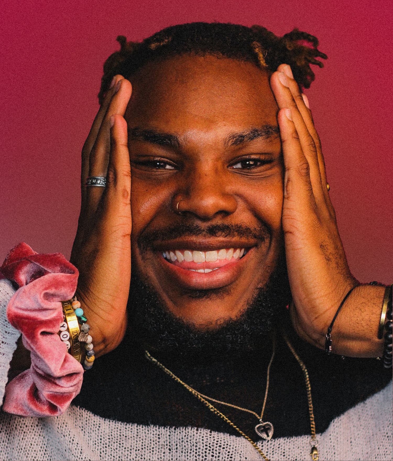Person in gray sweater showing various expressions against pink background with hands framing their face.