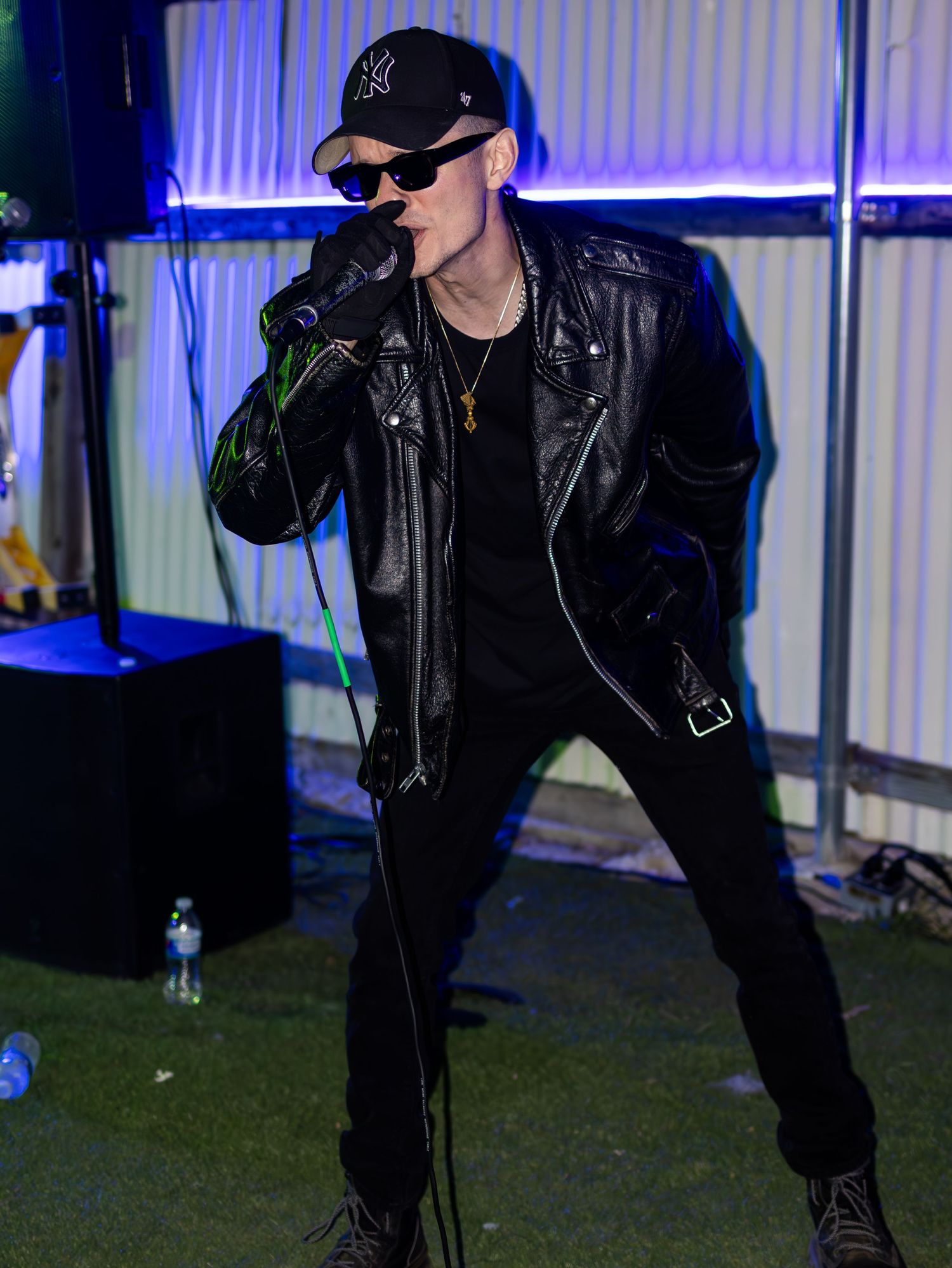 Performer in black outfit and cap delivering dynamic stage performance.
