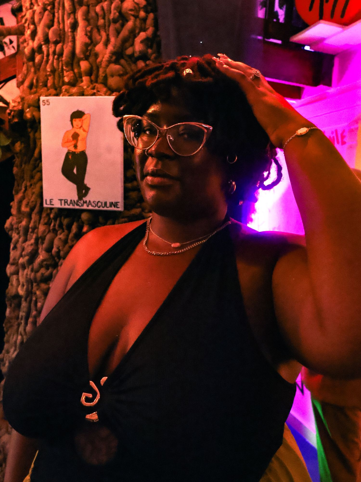 Person in black attire posing under pink mood lighting at an event.