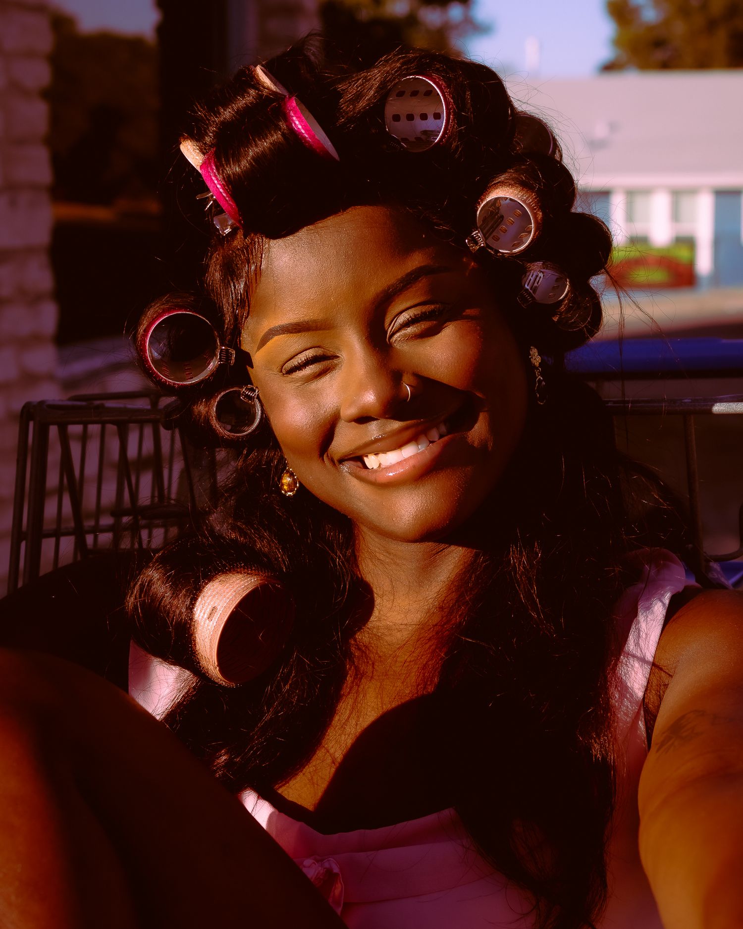 Candid portrait showing bright smile and pink hair rollers.