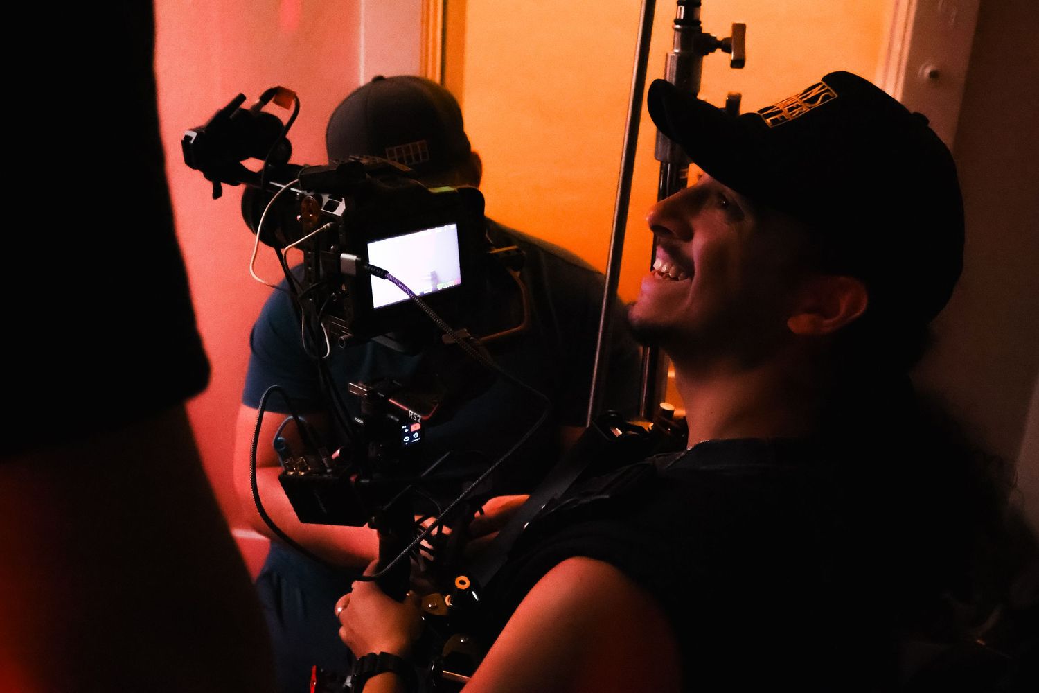 Film production team shooting in dark space with orange atmospheric lighting.