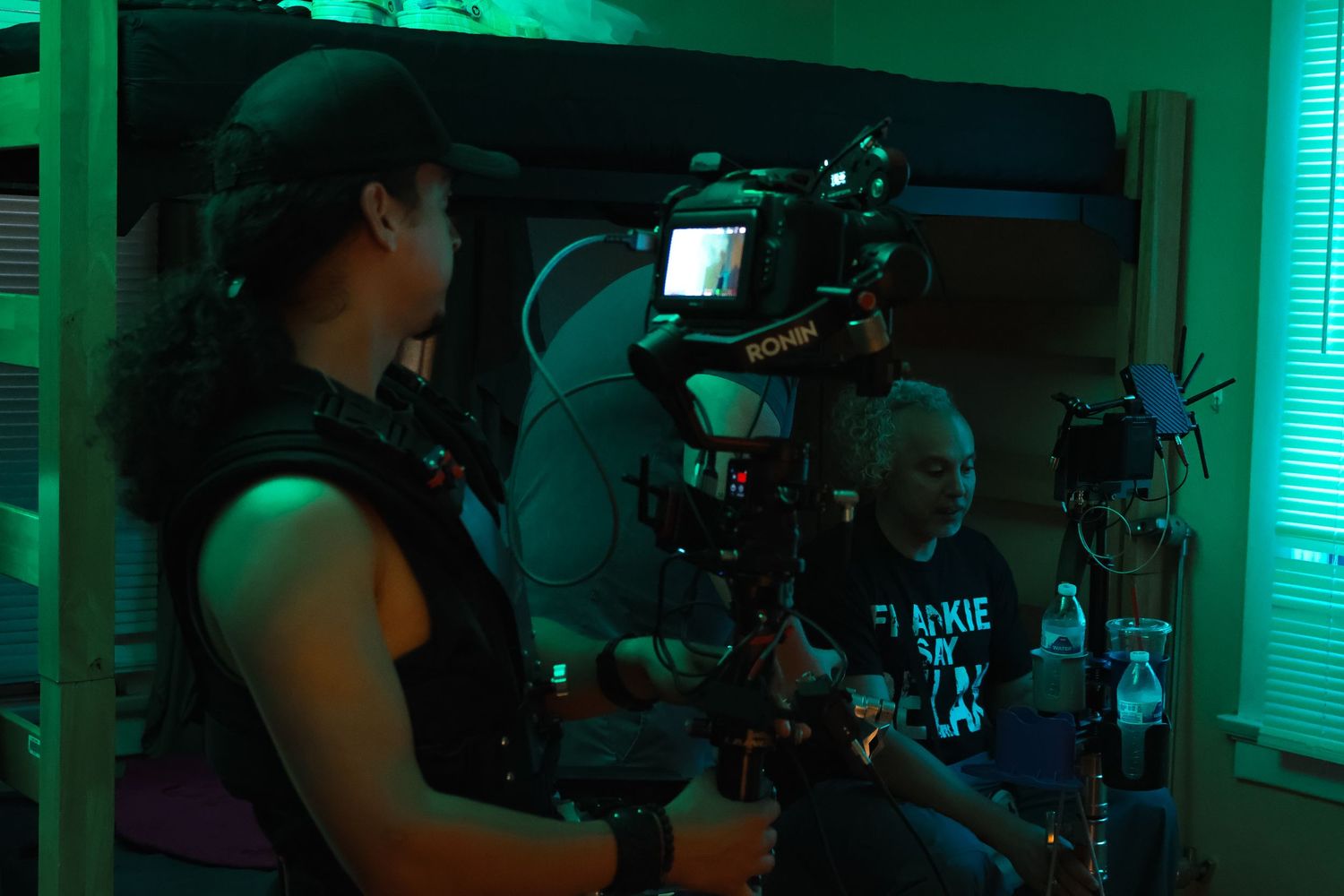 Film crew working with equipment under vibrant green lighting effects.
