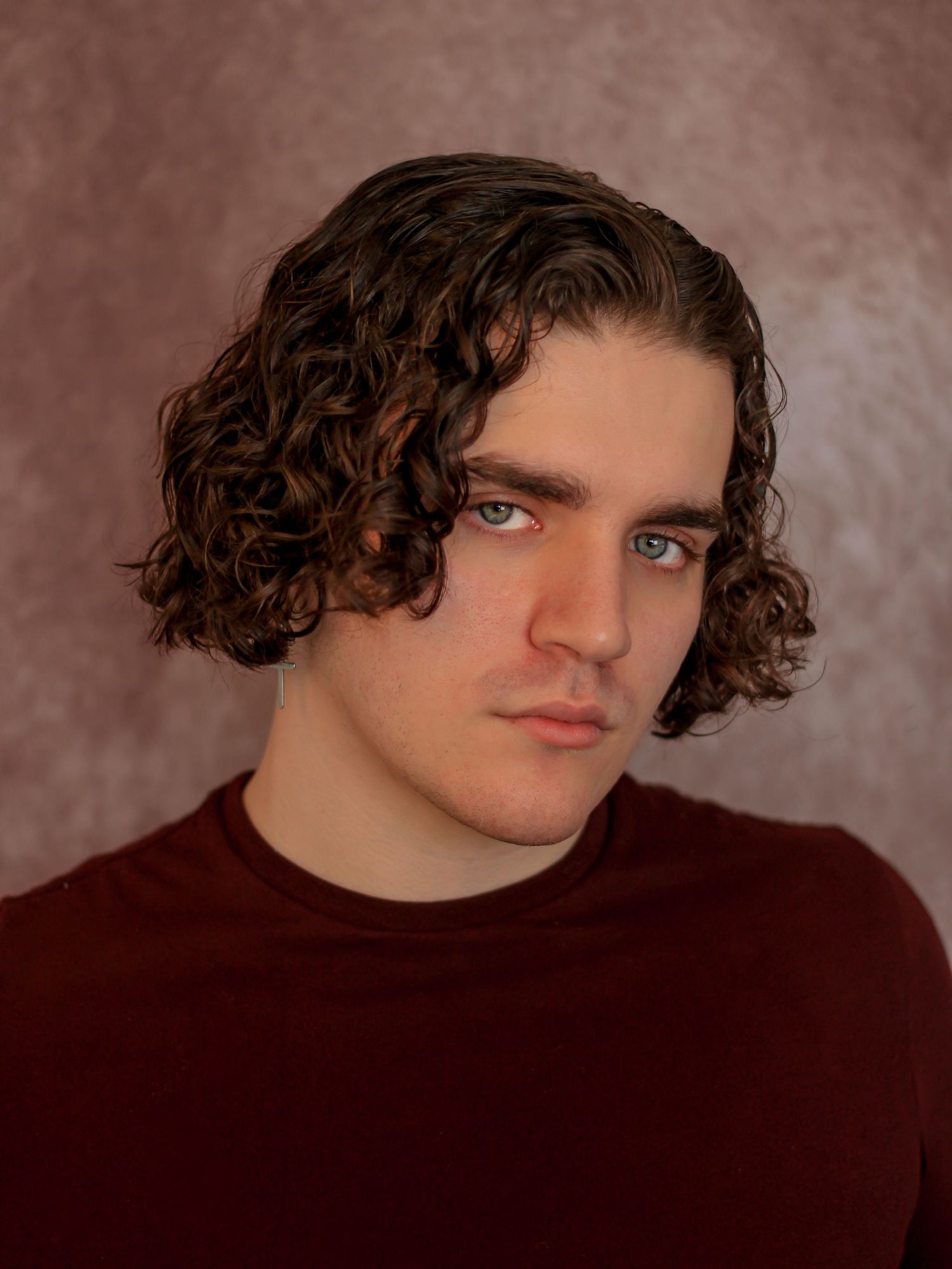 Portrait series showing different angles of person with curly hair wearing dark clothing against brown backdrop.