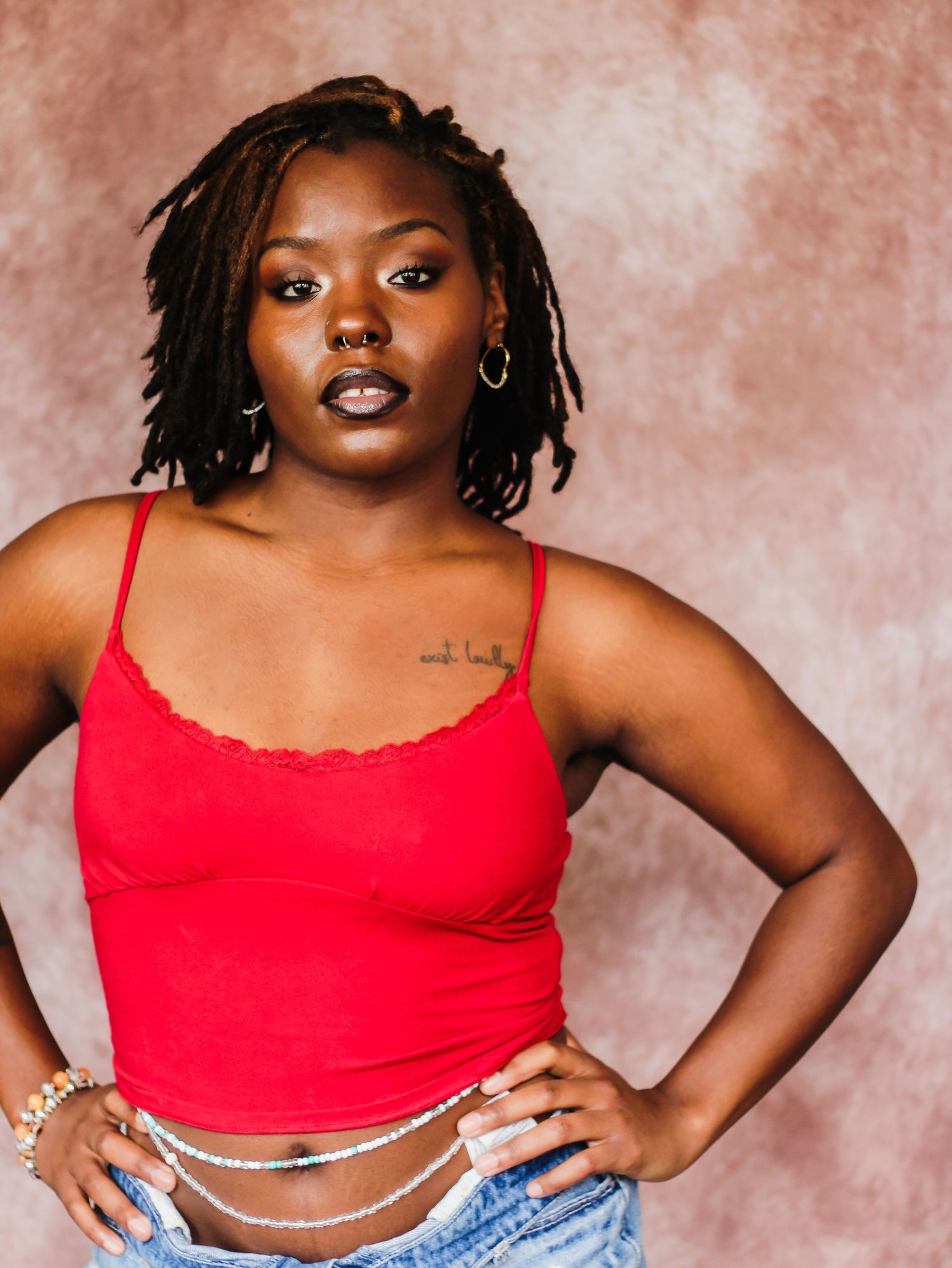 Fashion portraits in red crop top and denim against pink backdrop.
