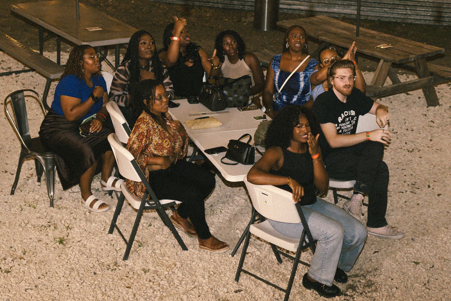 People relaxing at outdoor tables under evening lighting.