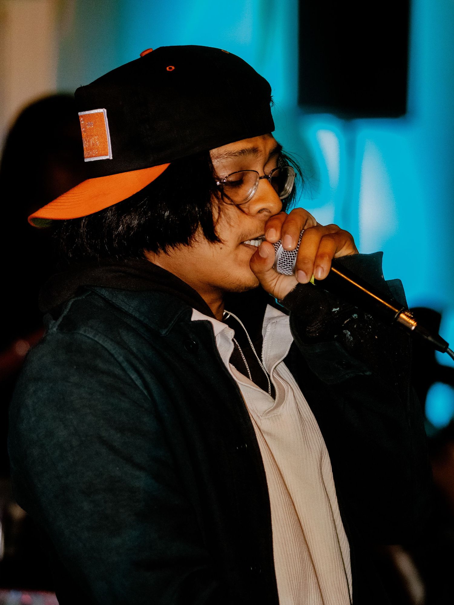 Close-up shot of performer with microphone under blue stage lighting.