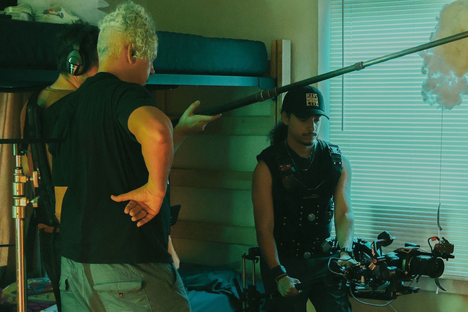 Behind-the-scenes film production crew working with equipment in a green-tinted room.