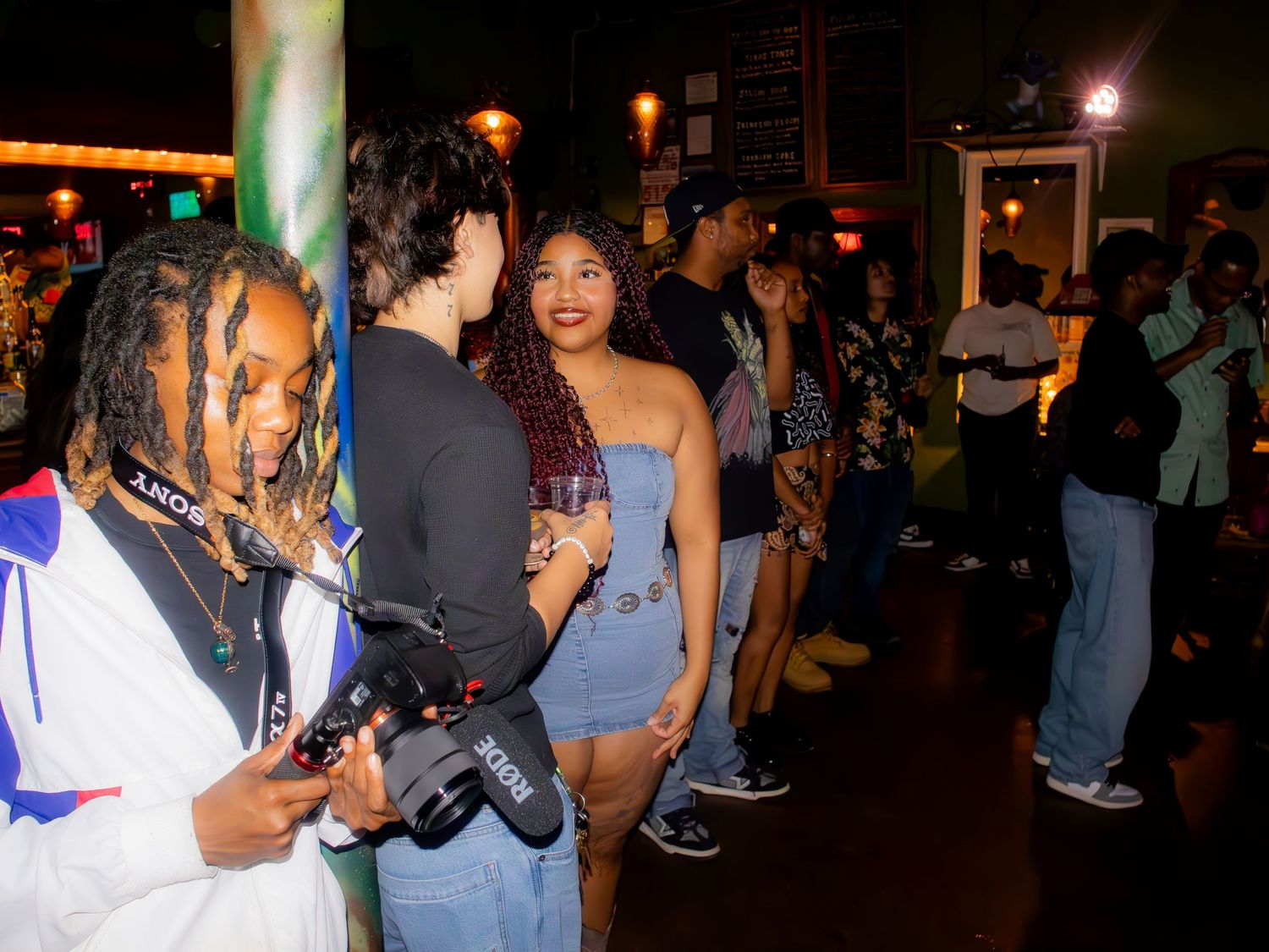 People mingling in a dark indoor space with ambient lighting.