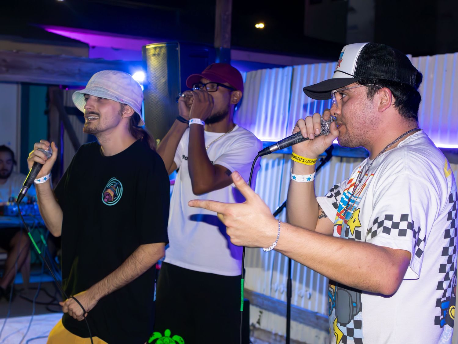 Concert performers singing into microphones with blue and purple stage lighting.