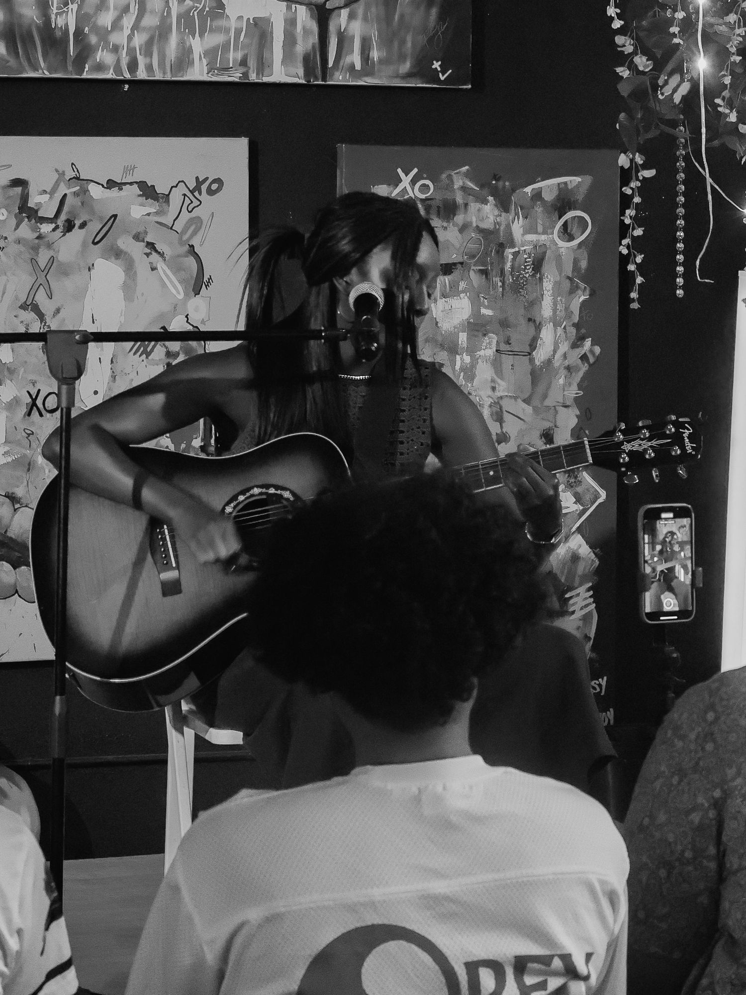 Black and white view of audience watching musical performance in intimate venue setting.