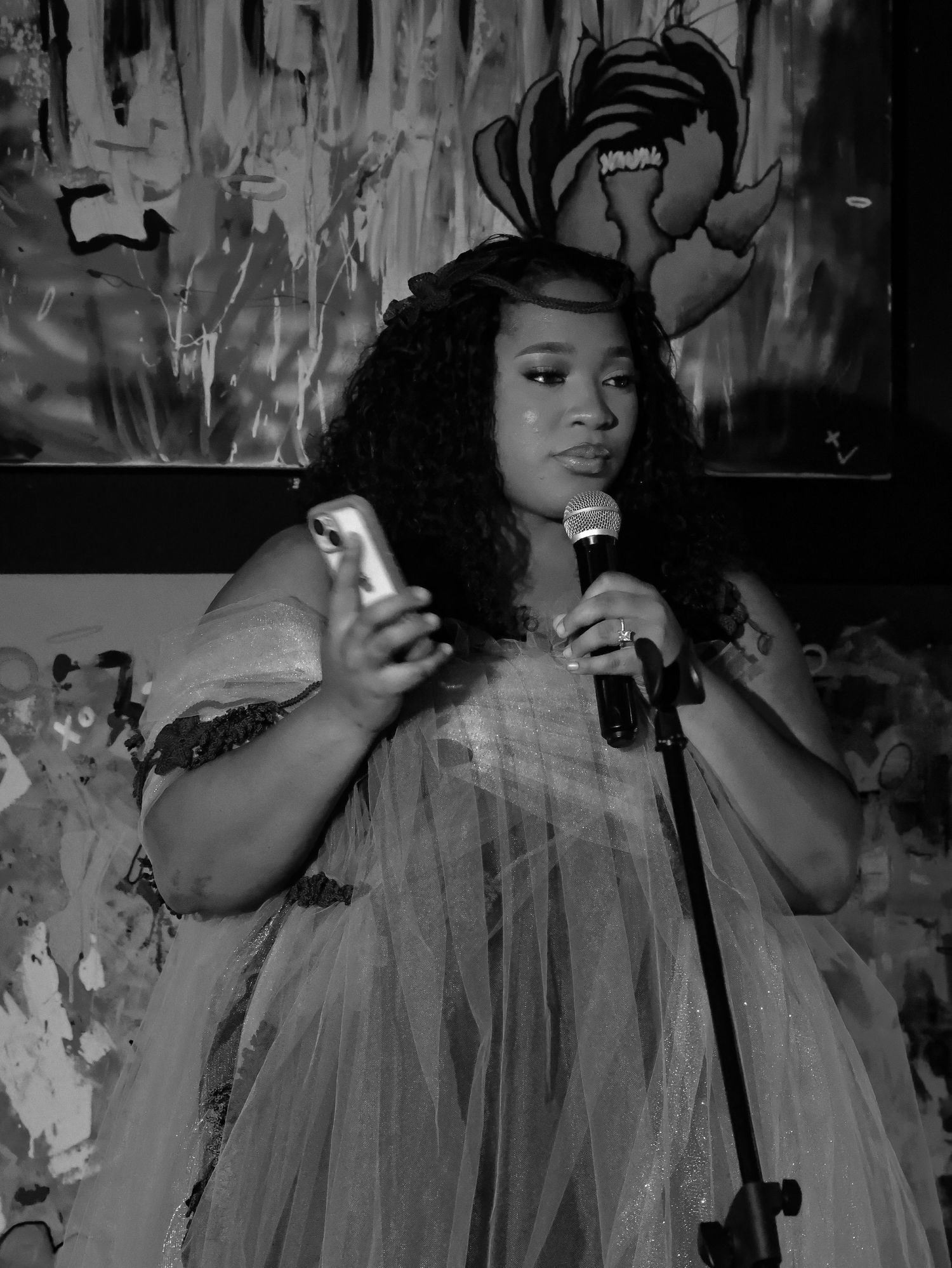Hazelnutproductions in flowing dress posing against textured wall in black and white photo at RichesArt Gallery in Austin, Texas