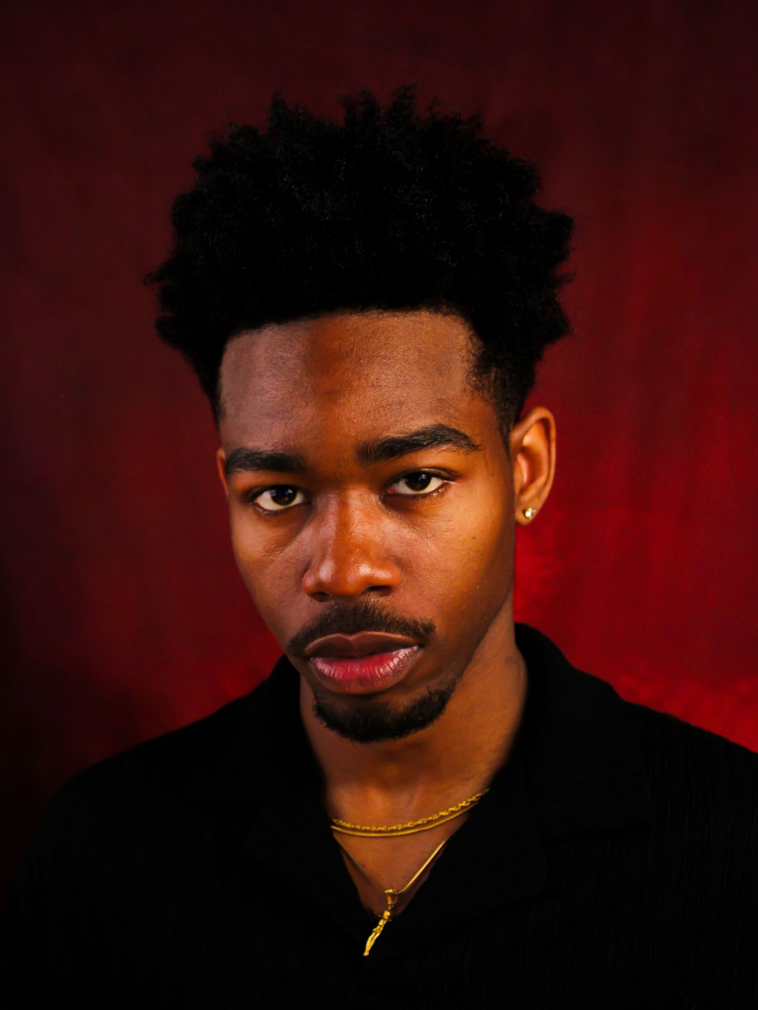 Dramatic portrait series with dark lighting against deep red background.