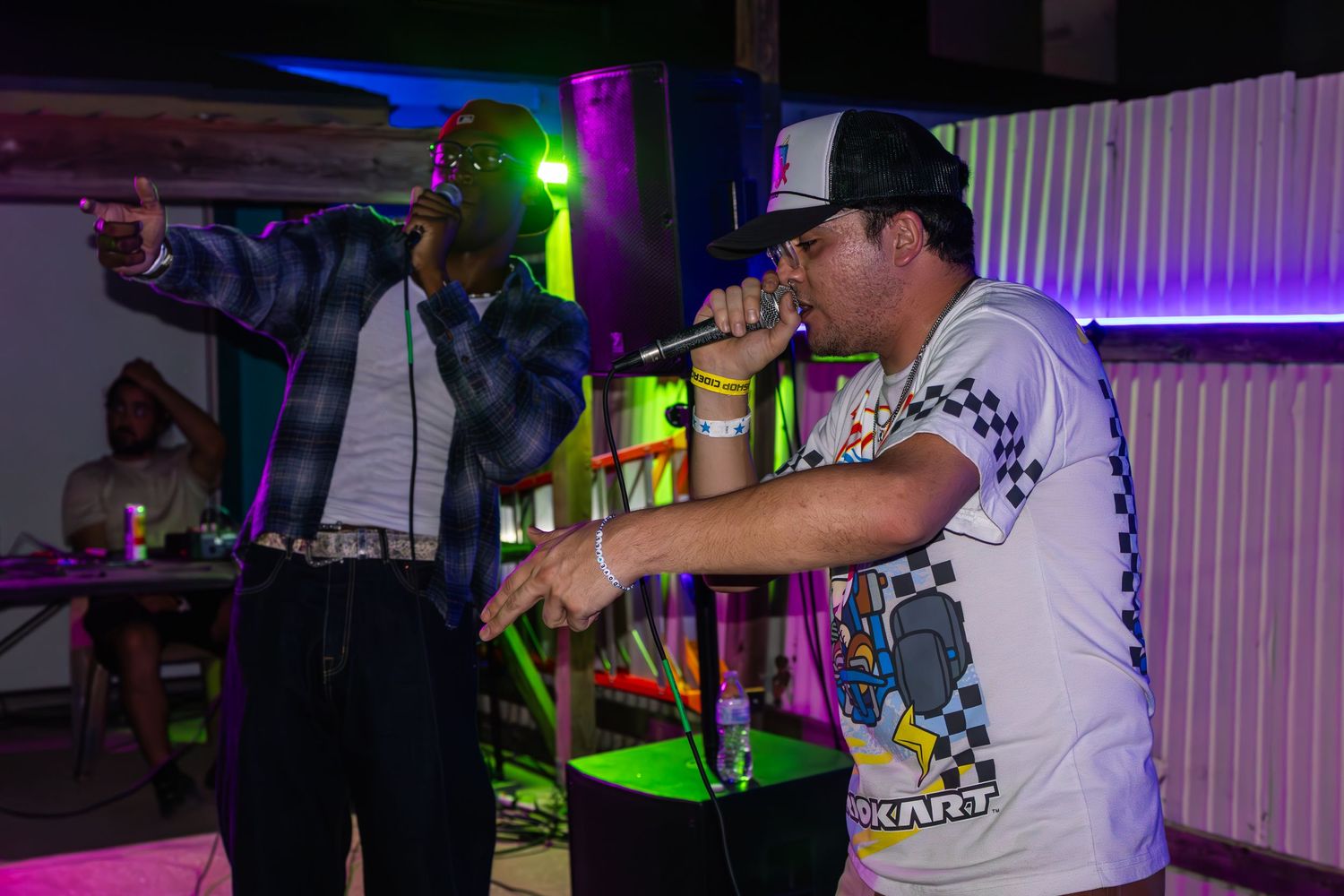 Live music performance at nightclub with colorful stage lighting and performers in casual attire.